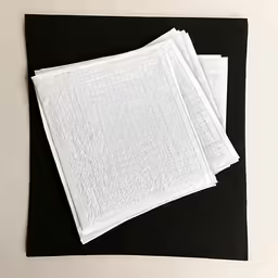 three towels, one with a checkered design on them, sit atop a black mat