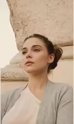 a close - up photo of a young woman posing in front of the ancient architecture of her town