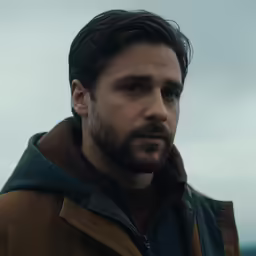 a man with a goatee looks into the distance