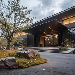 the walkway outside of the building leads to a tree and stone bench