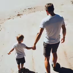a man holding the hand of a small child on a skateboard