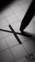 a pen on a piece of paper that has crosses painted on it,this photo shows a pen on a cross on a squared paper