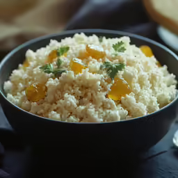 a black bowl filled with rice and oranges