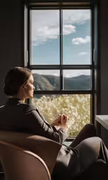 a woman sitting in a chair with her feet up against a table looking out a window
