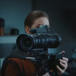 a woman is operating a camera on a tripod