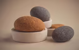 four bowls sit next to each other with two rocks inside