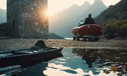 the man sits next to his car and canoes as he sits at the lake