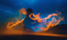 the silhouette of a man against an orange and blue sky