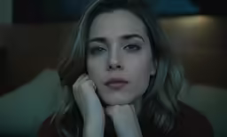 a woman sitting next to a lamp on top of a bed