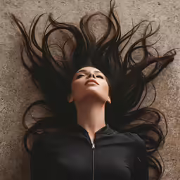 a woman with long brown hair looking at the sky