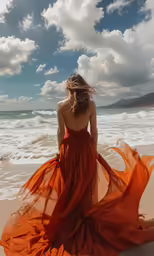 a beautiful woman in an orange dress sitting on the beach