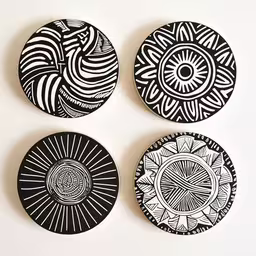 three hand made black and white plates on a white background,four circular, hand made ceramics are arranged in a series