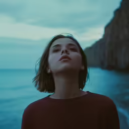 a woman stands on the edge of a cliff overlooking the water
