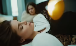 a young woman laying on top of a bed next to a pillow