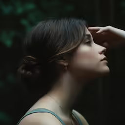 a woman looking off in the distance with her hand to her forehead