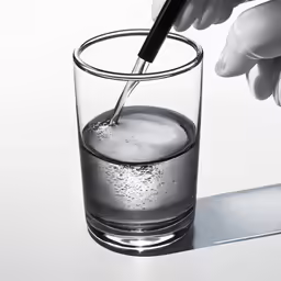 a person is holding an object over a glass