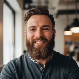 the man is smiling at the camera with a beard