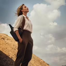 a woman standing on top of a rock under a cloudy sky
