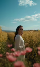 a young woman in a field is shown, looking into the distance