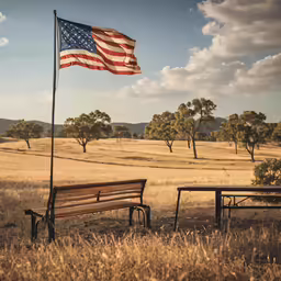 a bench and an american flag in a field