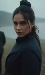 a woman standing with her head up next to a body of water