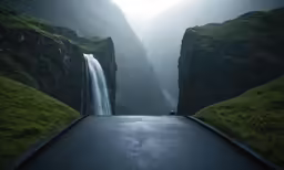 a car traveling down a long road with a waterfall coming out