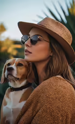 a woman with sunglasses and hat holding a dog