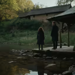 a man and a woman in medieval clothing are standing on a dock