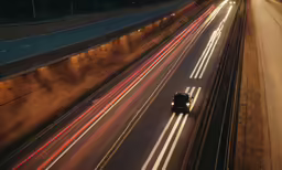 car lights streaking down the road below highway signs