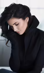 a woman in black is sitting on a white couch