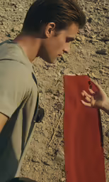 a man holding a book over his shoulder on the beach