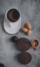 a cup of coffee and some nuts on a table