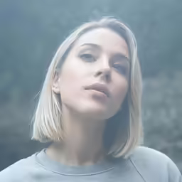 a woman with blonde hair and blue eyes looks forward