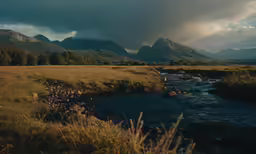 a stream running through a grass covered valley