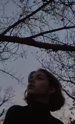 the woman is looking up through the trees