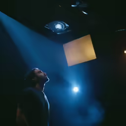a man standing in a darkened room by a flashlight