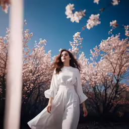 a woman wearing white with cherry blossom trees in the background
