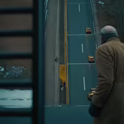 a person stands on the sidewalk looking over an empty highway