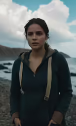 a woman standing on the side of a beach next to the ocean