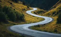 a long curved street in the mountains next to a winding road