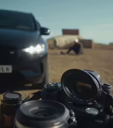 a car sits behind some cameras while a camera is sitting on a ledge