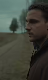 a man standing in the middle of a barren, grassy area