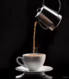a cup of coffee being poured into it with splashing orange juice