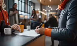 a woman is signing her paper at the table