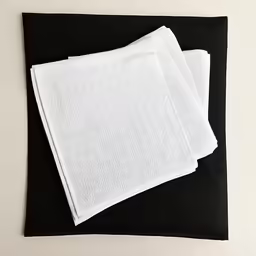a white towel is folded on top of a black square