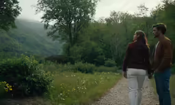 two people walking along a road in the woods