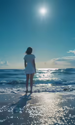 the woman stands on the beach in front of the water