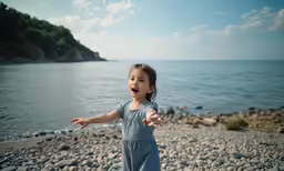 a little girl holding her arms out while walking on the rocks