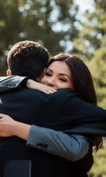 two people standing together embracing with trees in the background