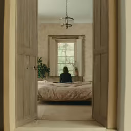 the girl is sitting in her bed in front of the window